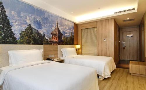 two beds in a hotel room with a painting on the wall at Atour Hotel Xi'an High Tech Dazhai Road in Xi'an