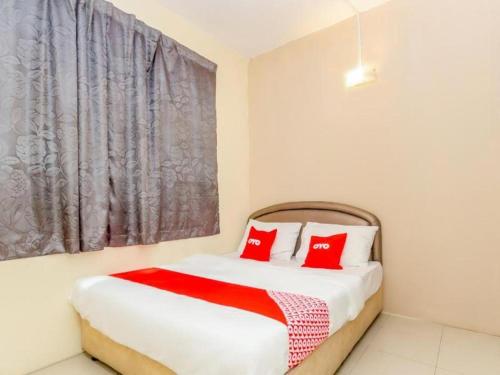 a bedroom with a bed with two red pillows at OYO 89703 B Link Hotel in Johor Bahru