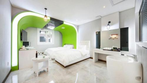 a bedroom with a white bed and a green wall at SH Hotel in Mokpo
