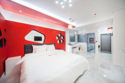 a bedroom with a white bed and a red wall at SH Hotel in Mokpo