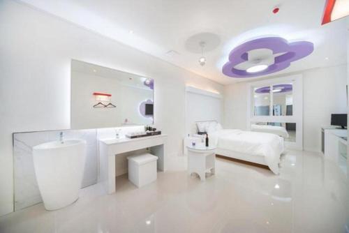 a white bathroom with a sink and a bed at SH Hotel in Mokpo