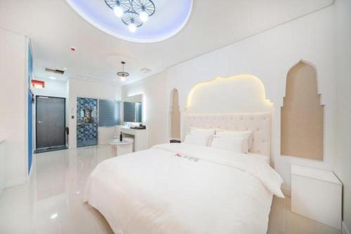 a white bedroom with a large white bed in it at SH Hotel in Mokpo
