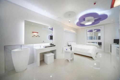 a white bathroom with a sink and a bed at SH Hotel in Mokpo