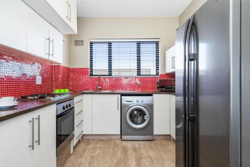 a kitchen with a washing machine and red tiles at Witsand 102 by Host Agents in Bloubergstrand