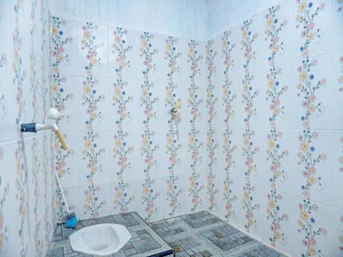 a bathroom with a toilet on a tiled wall at SPOT ON 92392 Penginapan Vinccent22 Syariah in Tanjungraya