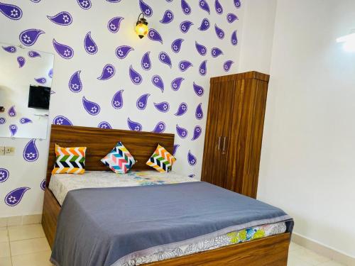 a bedroom with a bed and a purple and white wall at Candolim Beach Apartments Goa in Candolim