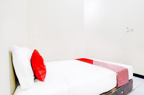 a bed with red and white pillows on it at Hotel O Ekslusive Double'n in Solo