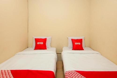 two beds in a room with red pillows at Hotel O 211 in Parapat