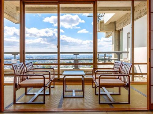 four chairs and a table in front of a large window at Ooedo Onsen Monogatari Minoh Kanko Hotel in Minoo