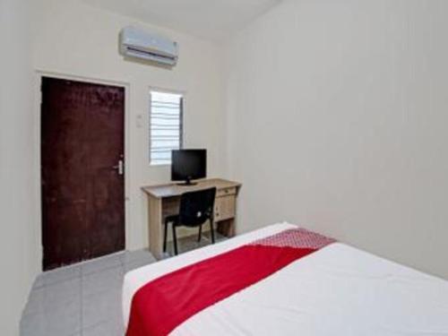 a bedroom with a bed and a desk with a computer at Hotel O Wonoayu Residence Syariah in Sidoarjo