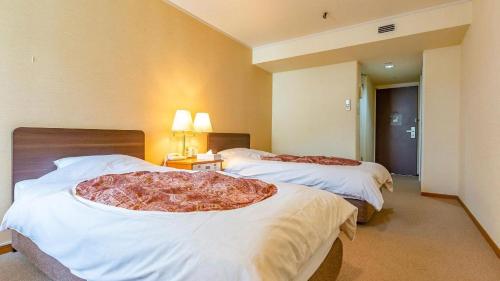 a hotel room with two beds with a large pillow on them at Ooedo Onsen Monogatari Minoh Kanko Hotel in Minoo