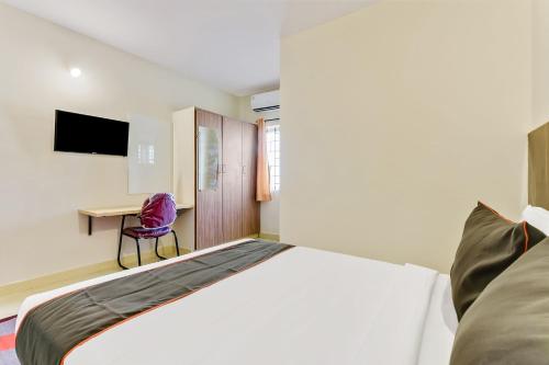 a bedroom with a large bed and a desk at Hotel O Vittala Comforts in Bengaluru