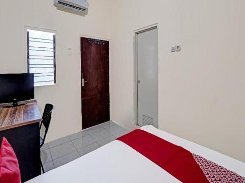 a bedroom with a bed and a desk and a door at Hotel O Wonoayu Residence Syariah in Sidoarjo