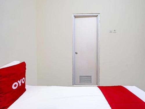 a door in a room with a red blanket at Hotel O Wonoayu Residence Syariah in Sidoarjo