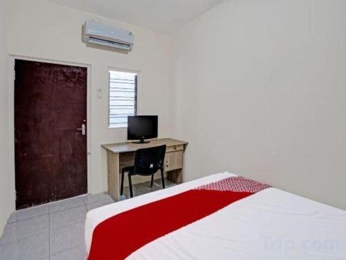 a bedroom with a bed and a desk with a computer at Hotel O Wonoayu Residence Syariah in Sidoarjo