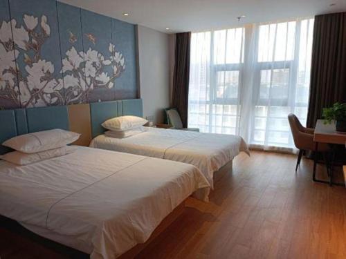 a hotel room with two beds and a desk at Jinjiang Inn Yancheng Funing Harbin Road in Yancheng