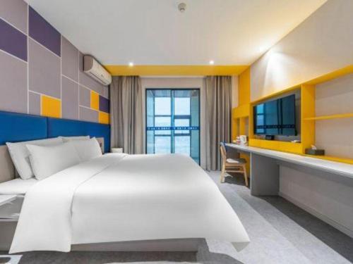 a bedroom with a large white bed and a desk at 7 Days Inn Guangrao Bus Station in Dongying