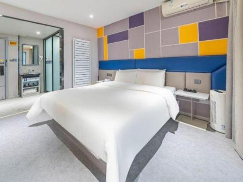 a large white bedroom with a large white bed at 7 Days Inn Guangrao Bus Station in Dongying
