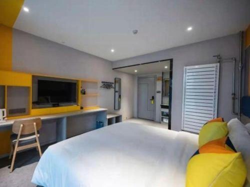 a bedroom with a large white bed and a desk at 7 Days Inn Guangrao Bus Station in Dongying