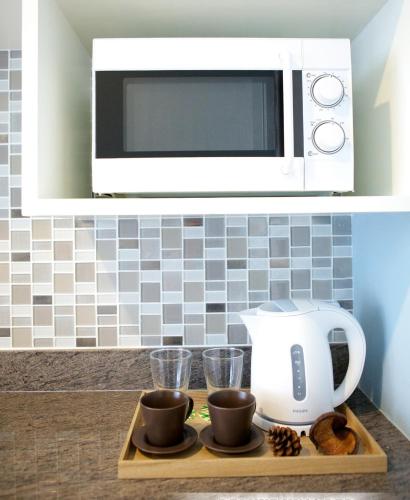 a microwave above a counter with a coffee maker and cups at Cinnamon Hotel Bangkok in Bangkok
