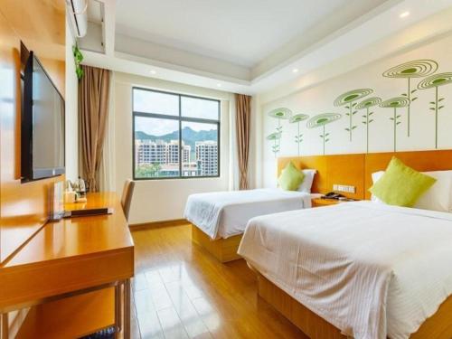 une chambre d'hôtel avec deux lits, un bureau et une télévision dans l'établissement GreenTree Alliance Sanya Jiyang District Yalongwan Road Hotel, à Da'ancun