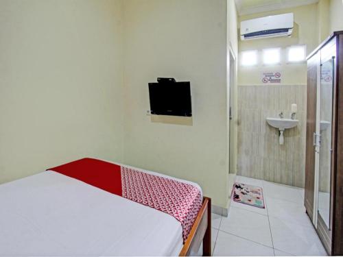 une chambre avec un lit et une salle de bain avec un lavabo dans l'établissement Capital O 93124 Lombok Northis Homestay, à Paloh