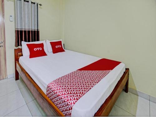 une chambre avec un lit avec des oreillers rouges dessus dans l'établissement Capital O 93124 Lombok Northis Homestay, à Paloh