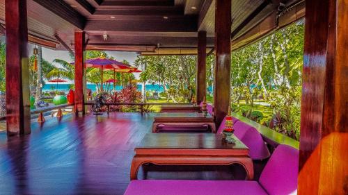 a restaurant with purple tables and chairs and the ocean at Baan Thai Lanta Resort in Ko Lanta
