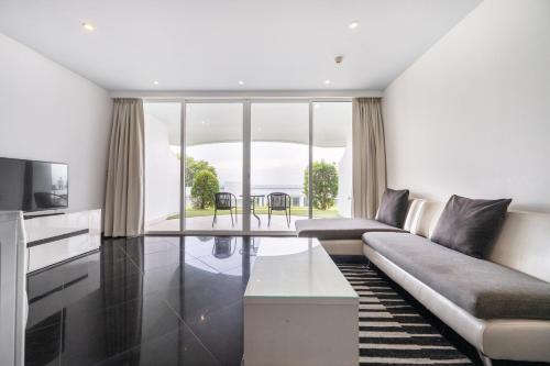a living room with a couch and a television at Pure Sunset Beach - Ocean View Room, Pattaya in Na Jomtien