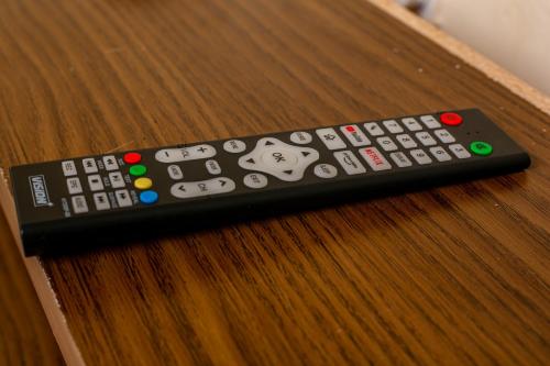 a remote control sitting on top of a wooden table at Furnished Cozy One Bedroom Apartment in Busia