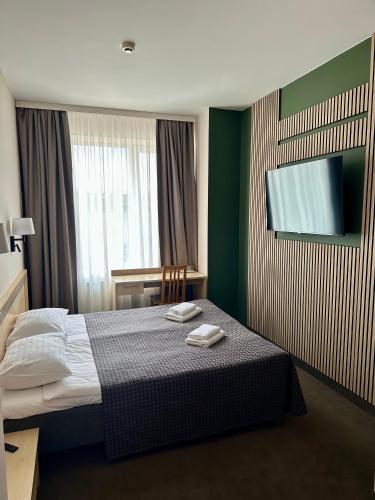 a hotel room with a bed and a flat screen tv at VESK Svečių Namai in Druskininkai