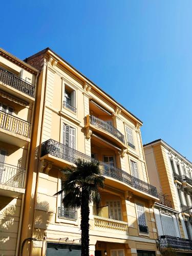 un grand bâtiment avec un palmier devant lui dans l'établissement Dolce Cannes Riviera Cannes, à Cannes
