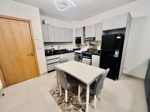 a kitchen with a white table and a black refrigerator at Luxury Chalet with Private Garden & Pool View in Marassi in El Alamein