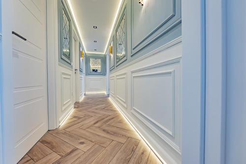 a hallway with white walls and wood flooring and a door at ONE66 - Luxury Aparthotel in Braşov