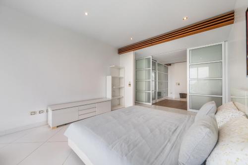 a white bedroom with a large bed and a mirror at Pure Sunset Beach - Ocean View Room, Pattaya in Na Jomtien