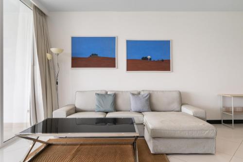 a living room with a couch and a glass coffee table at Pure Sunset Beach - Ocean View Room, Pattaya in Na Jomtien