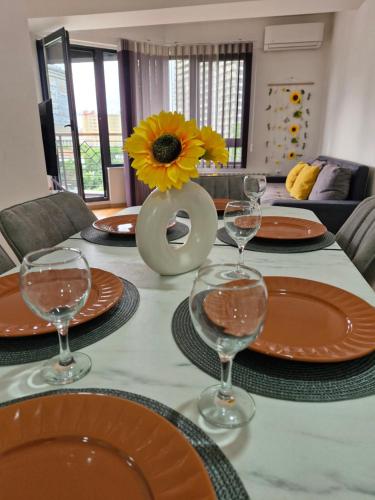 a table with plates and glasses and a vase with a sunflower at Sunflower City Center with free garage in Skopje