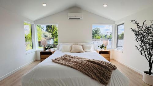 a white bedroom with a large bed and windows at Brand New Architectural Gem 1900 sqft House with SPA bathroom 15min to downtown in Seattle