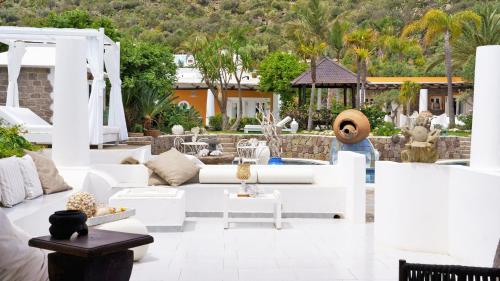 a living room with white furniture and palm trees at Hotel Oasi in Panarea