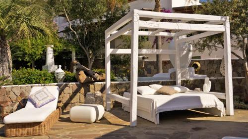 a white bed and a chair in a yard at Hotel Oasi in Panarea