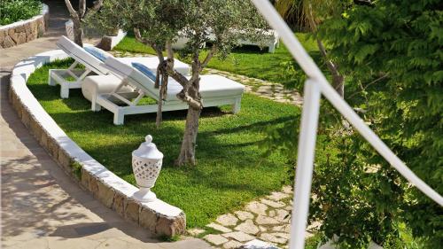 a garden with two lounge chairs and a tree at Hotel Oasi in Panarea