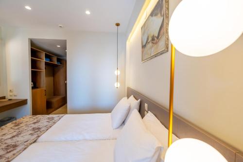 a bedroom with a bed with white sheets and a lamp at Country Inn in Kallithea Halkidikis