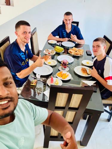 a group of men sitting around a table eating food at Ahasna Airport Villa in Negombo