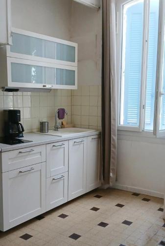une cuisine avec des armoires blanches et une fenêtre dans l'établissement Le Victor Hugo - centre ville, à Salon-de-Provence