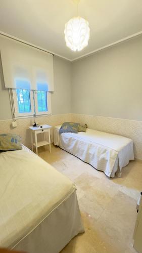 a bedroom with two beds and a chandelier at BAJO EN COSTA GADIR in Chiclana de la Frontera