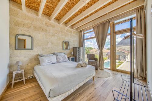 a bedroom with a bed and a large window at La Grange De La Maison Reverdi in Lamarque