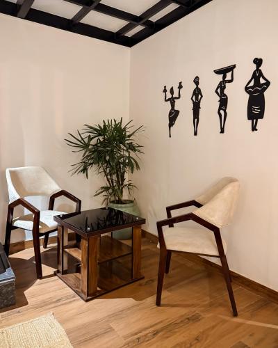 a living room with a table and two chairs and a wall at Tanay Stays in Mārg Āsni