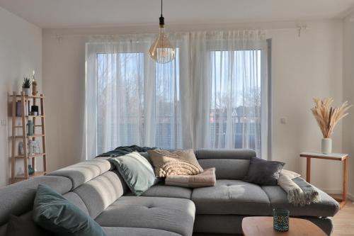 a living room with a gray couch in front of windows at Fewo Meery in Bad Doberan