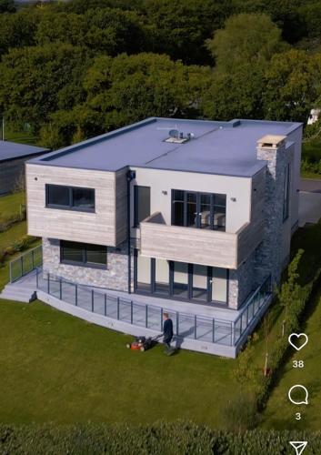 a man standing in front of a house at Modern 5 Bedroom Luxury Home with Sea Views and Hot Tub in North Hayling