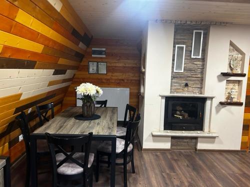 a dining room with a table and a fireplace at Romantica Forest Guest House in Dospat